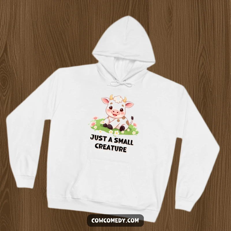 Funny hoodie design showing a small cow with legs in the air, blissfully rolling amidst a dense field of green clover.