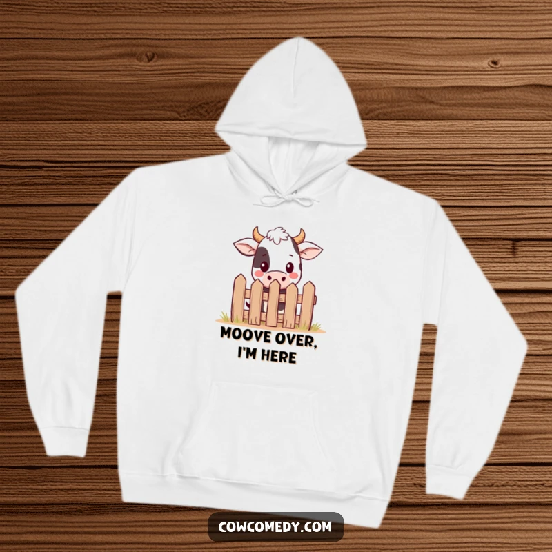 Funny kawaii cow hoodie showing a shy, cute cow peeking from behind a small, whimsical fence, offering warmth and humor.