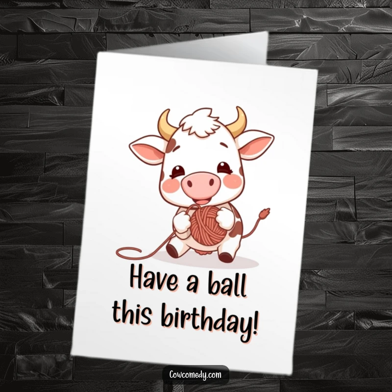 Funny Free Printable Birthday Card showing an excited cow joyfully bouncing a colorful yarn ball with its nose, full of energy.